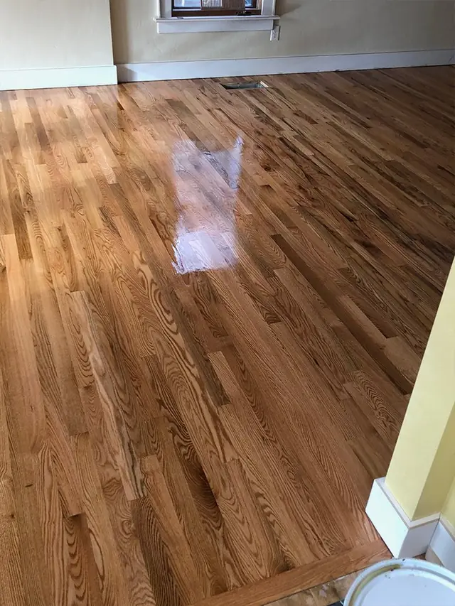Glossy oak plank floor running toward a pale yellow wall