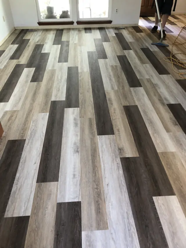 Grey and charcoal luxury vinyl plank floor in a room with French doors